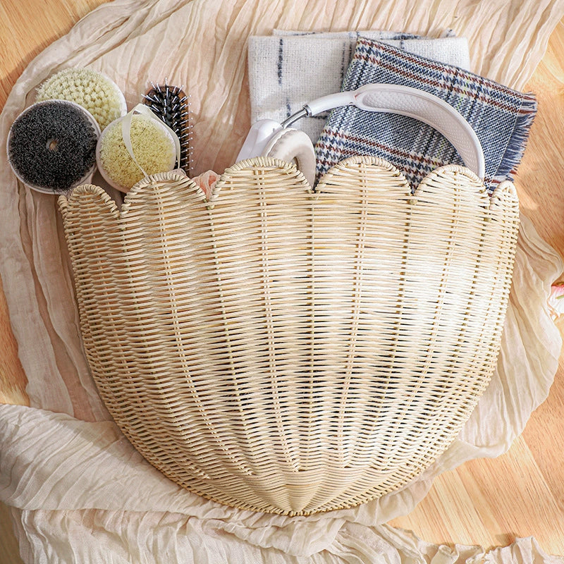Beige scalloped wicker wall basket with assorted brushes and fabric accessories.