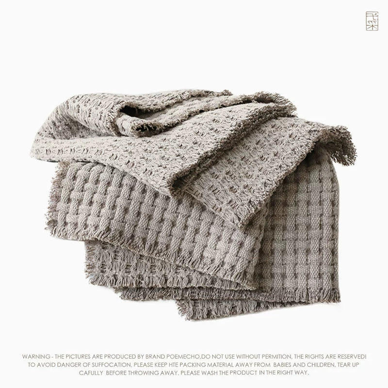 Beige woven cotton throw blanket, featuring a textured grid pattern and frayed edges.  Soft, cozy, and versatile.