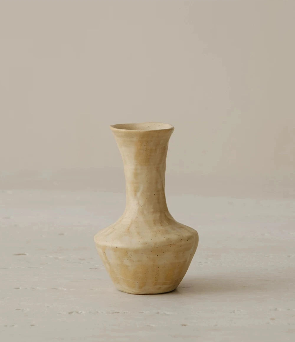 A small, hand-thrown ceramic vase with a textured, creamy white curd glaze and a narrow neck.