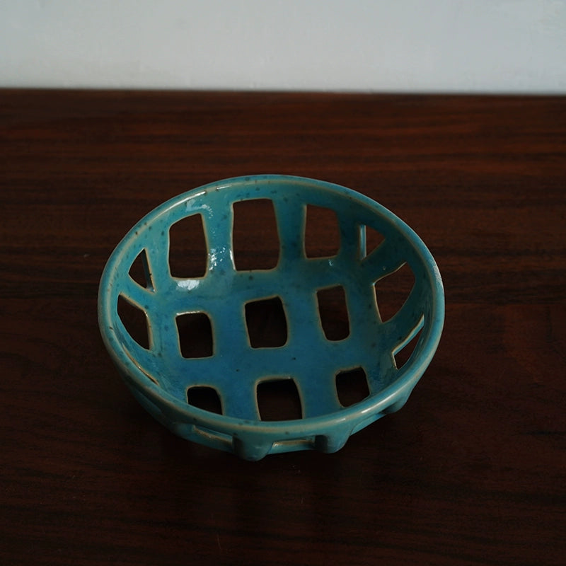 Teal ceramic fruit bowl with a hollow, lattice design.  Handmade, sesame-glazed.