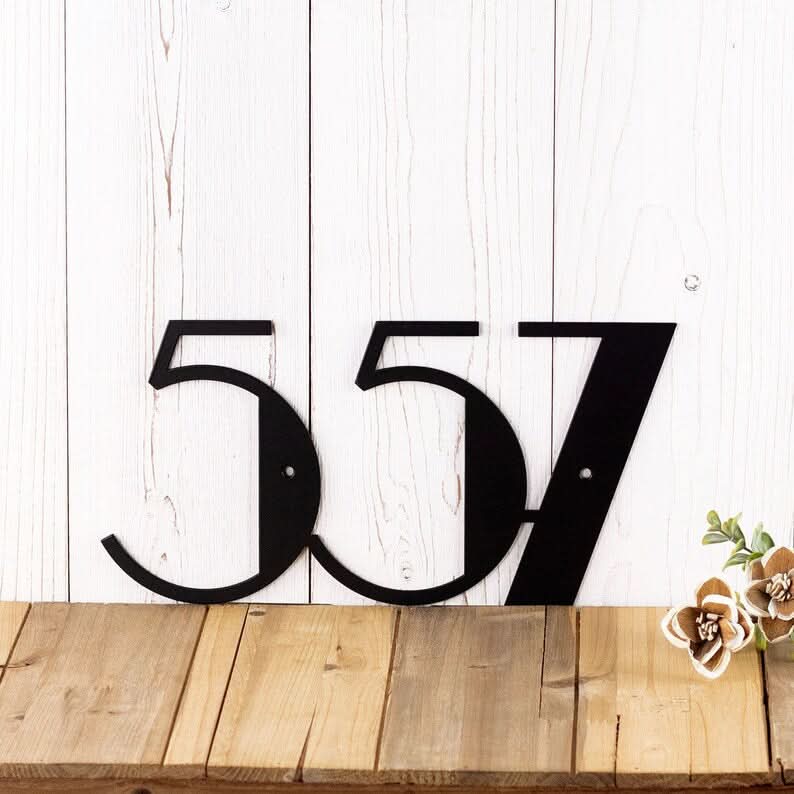 Black Mid Century Address Numbers "557" on a white wooden wall, home decor.