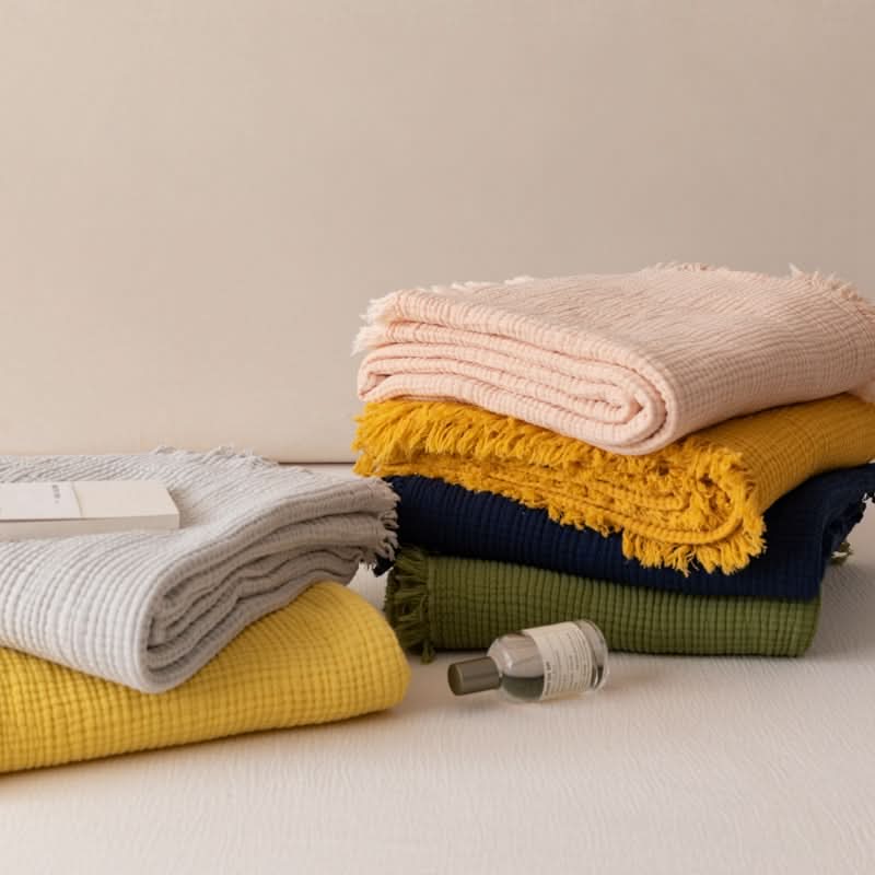 Stack of Four-Layer Waffle Weave Cotton Throws in pink, mustard, navy, and olive.