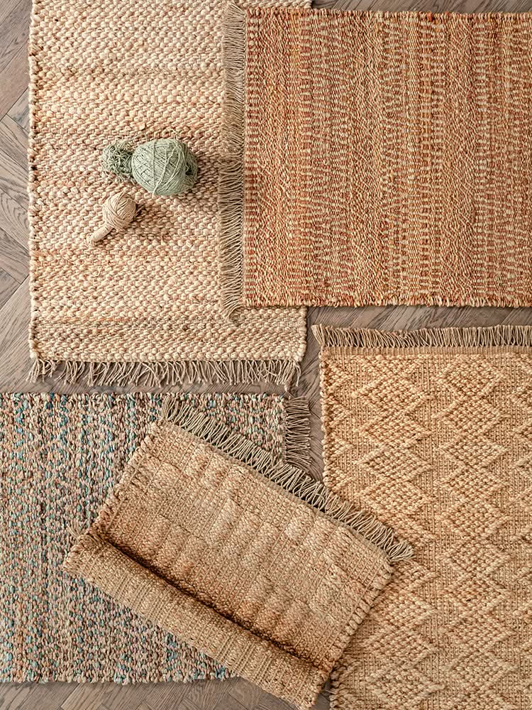 Natural woven area rugs in various textures and neutral tones with fringe detail.