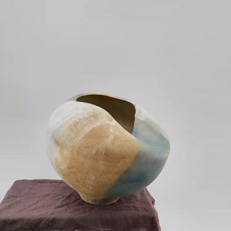 A handmade white ceramic vase with a unique sculptural, folded design.