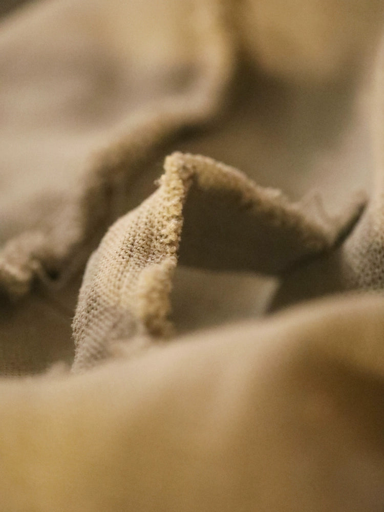 Close-up of beige textured fabric from a round ottoman pouf.