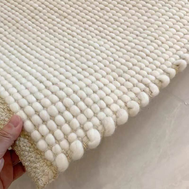 Close-up of Wool Handwoven Cream Rug, showing textured wool balls and woven edges.