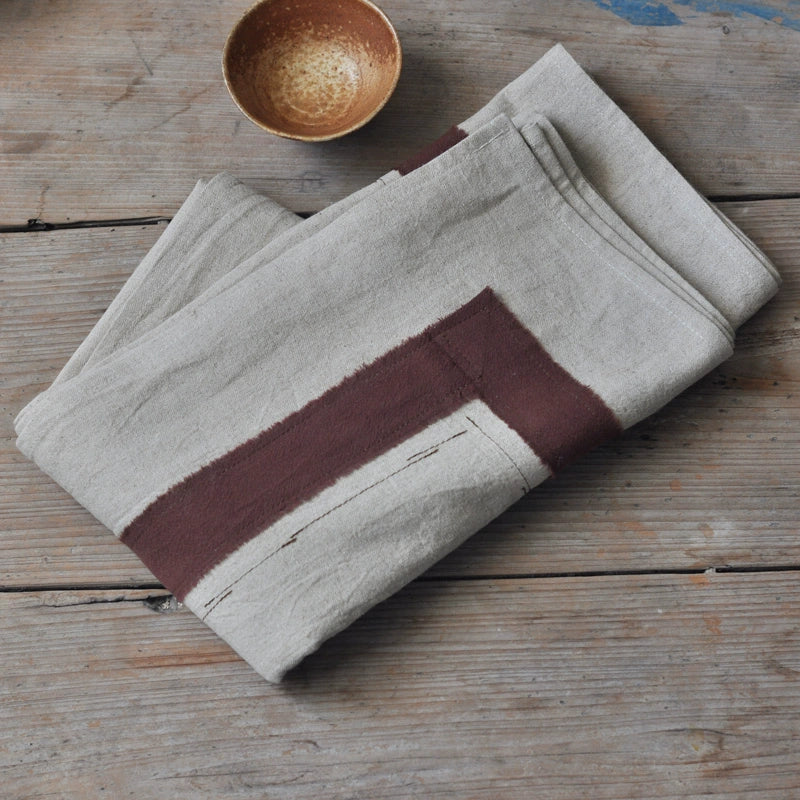 Rustic Linen Tablecloth with Striped Border, natural linen with a brown stripe, on a wooden table.
