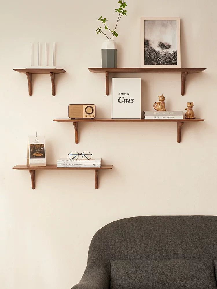 Walnut floating shelves displaying decor items above a dark gray sofa.