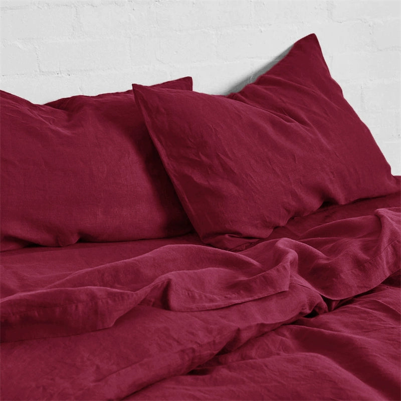 Deep red natural linen bedding set with soft, comfortable texture on a white brick background.