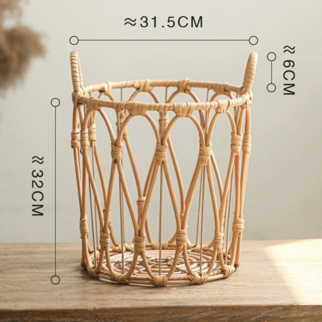 Light beige woven rattan storage basket with handles.  Round shape, decorative design.  Standing on a light wooden surface.