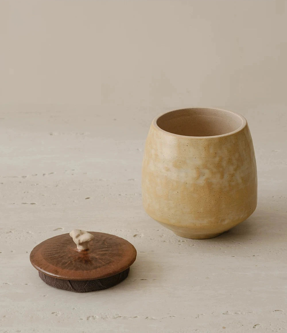 Curd-glazed ceramic storage jar with a natural wooden lid and a unique artisanal finish.