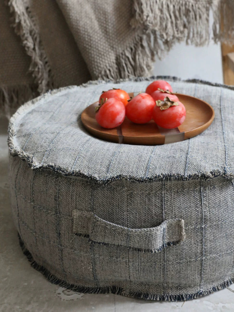 Round beige fabric ottoman pouf with decorative accent seating, home decor.