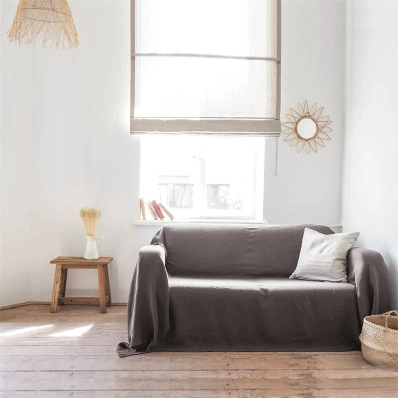 Mustard yellow linen sofa throw blanket draped over a grey sofa in a bright living room.