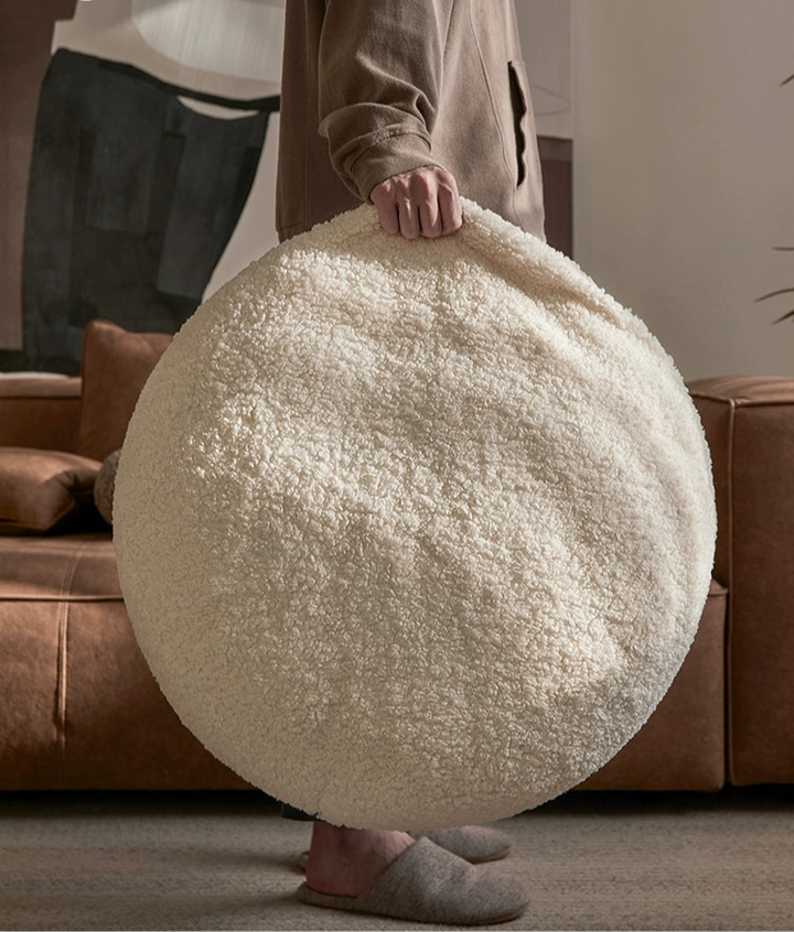 Fluffy cream-colored bean bag chair, round shape, sherpa-like texture. Cozy seating.