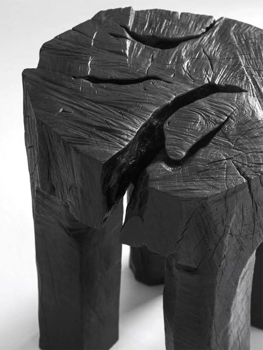 Raw wood block side table in dark charcoal finish, textured natural form.