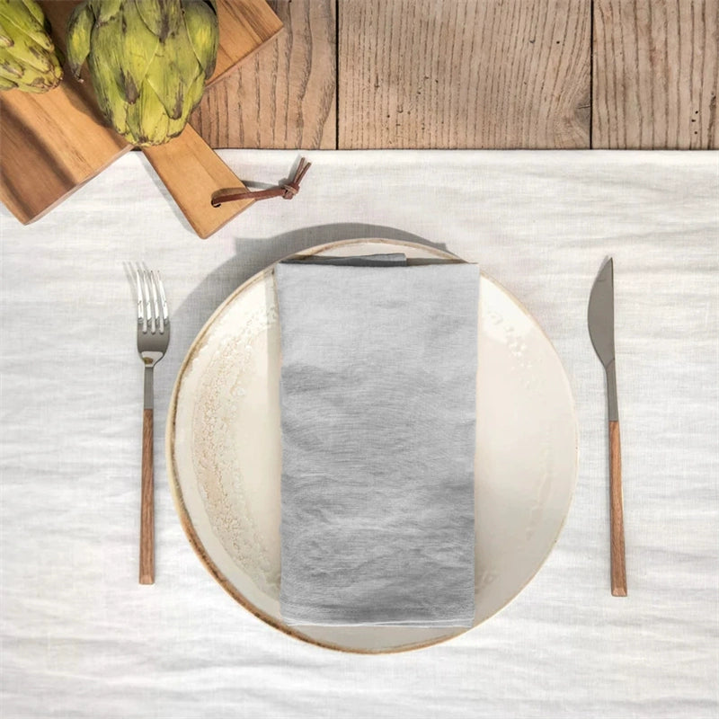 Elegant linen table napkins, grey, set of 4, on plate with fork and knife.