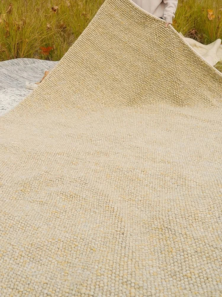 Close-up of a textured cream handmade wool rug, luxurious and cozy, perfect for home decor.
