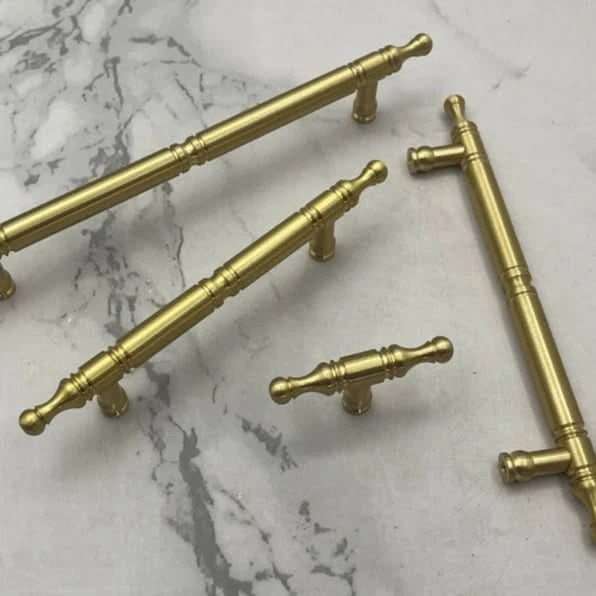 Solid brass cabinet handles, classic style, on marble surface.
