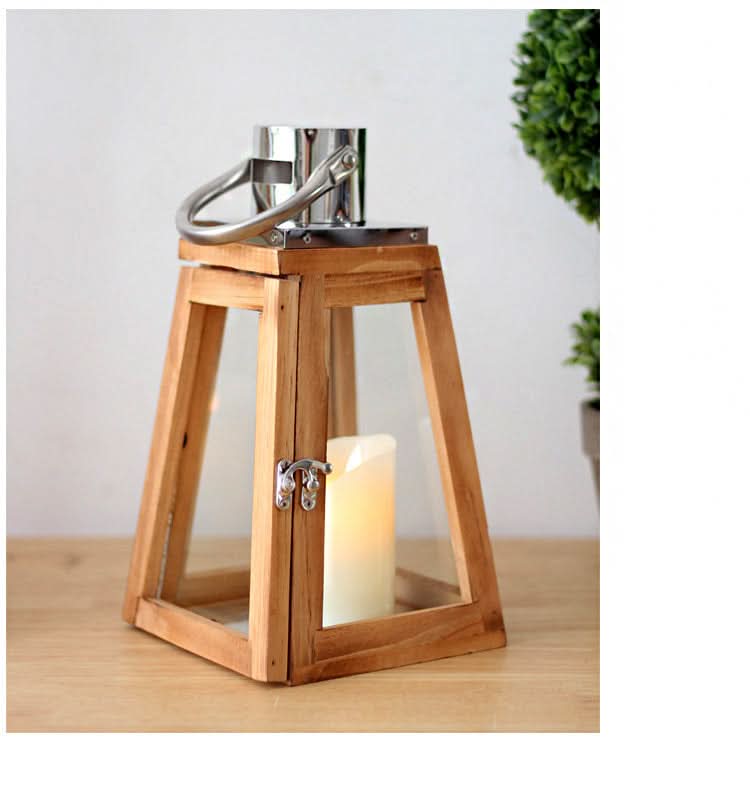 Triangular rustic wooden lantern with glass panels and a lit candle inside, on a wooden table.