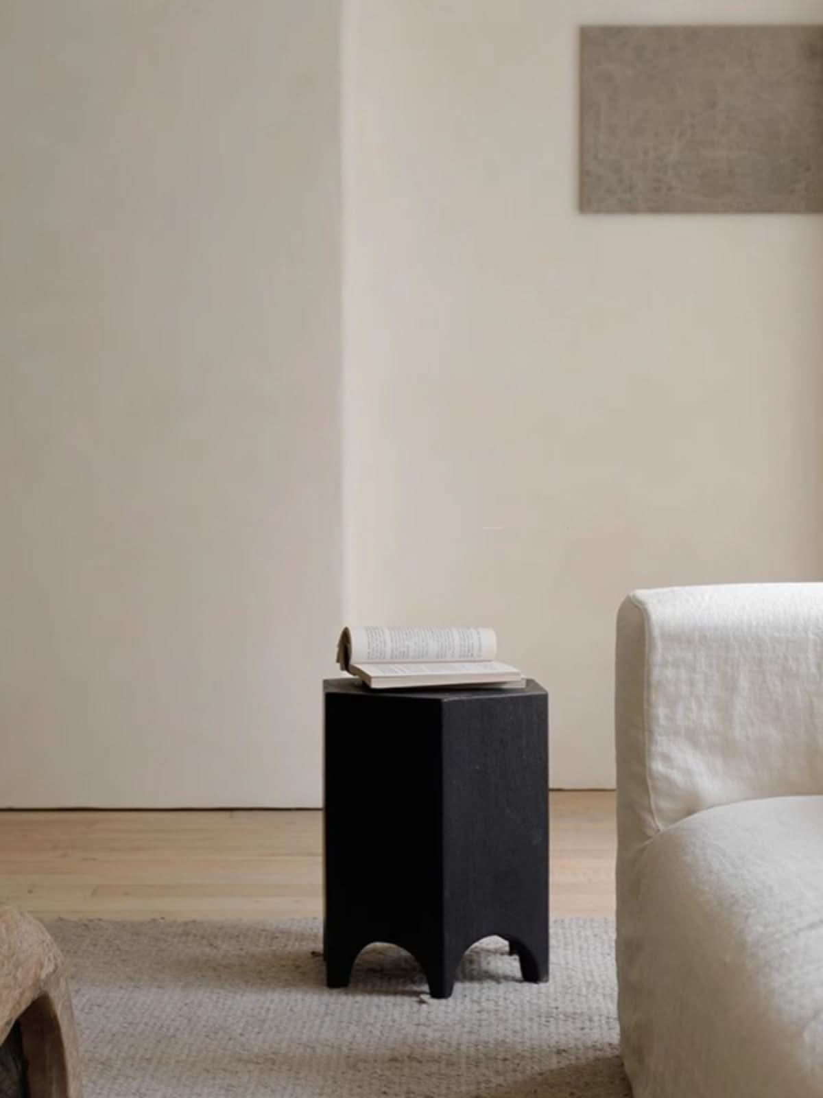 Minimalist black hexagonal side table with a book, in a modern room setting.