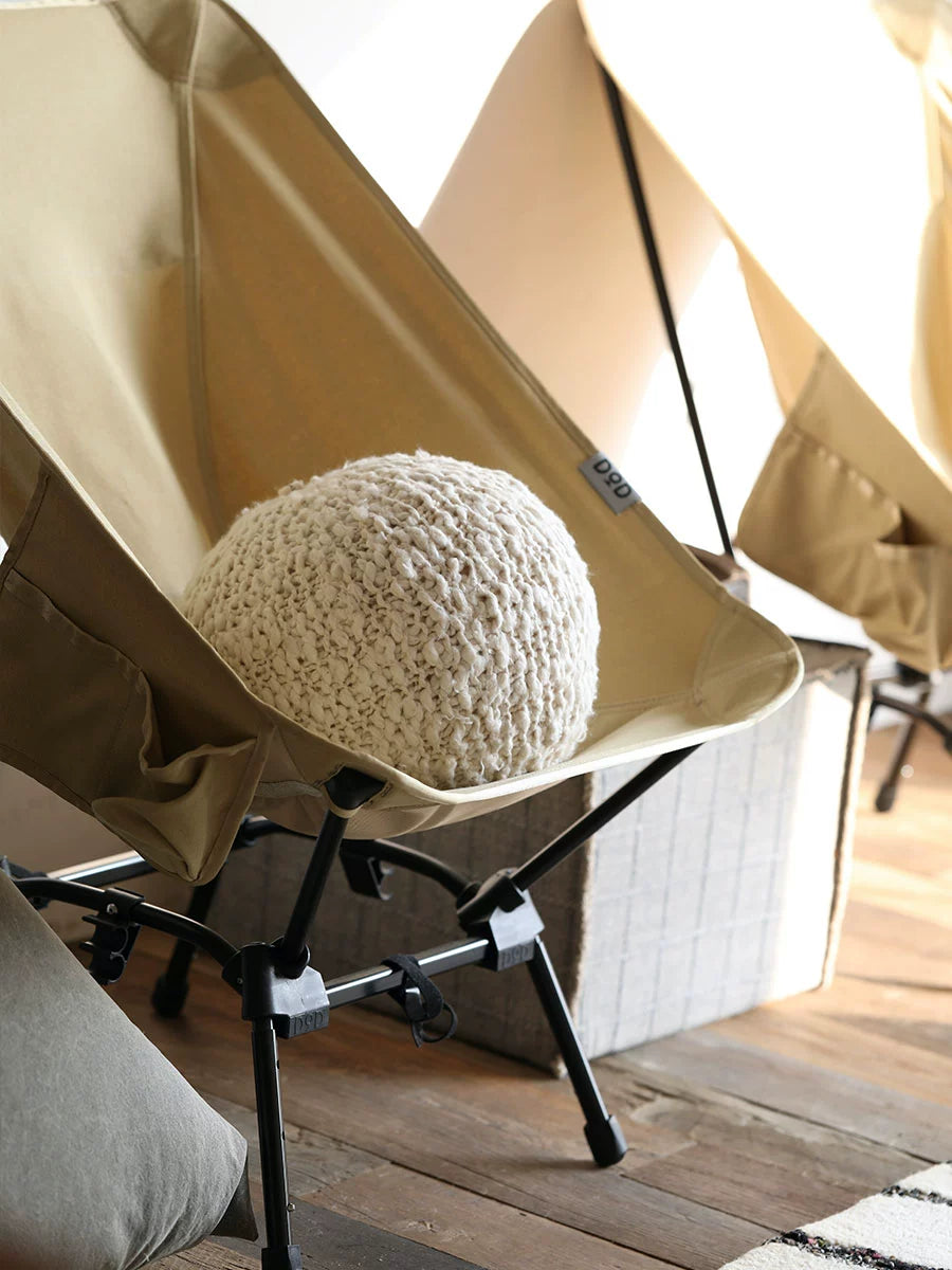 Cozy knitted throw pillow in cream on a tan chair, part of the set of 4.