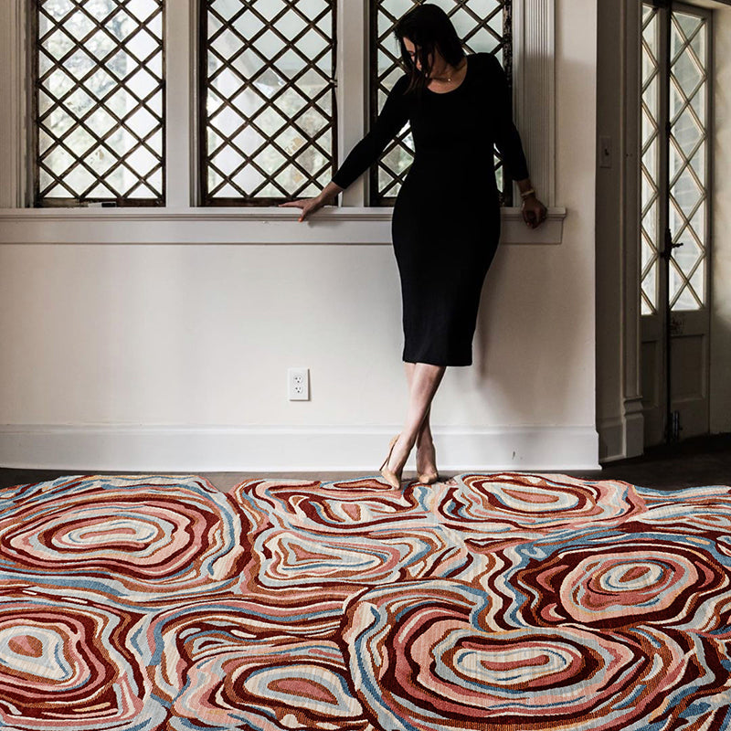 Unique abstract rug with rings of red, tan, blue, and cream on a floor, styled as a living room accent.