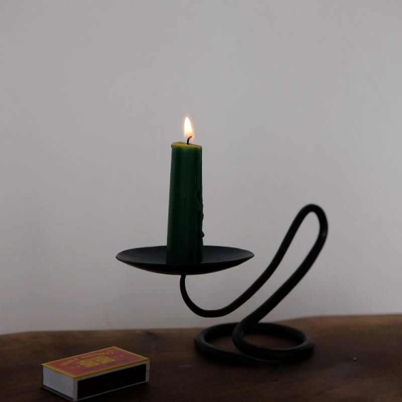 Stylish black candle holder with a green candle on a wooden surface, home decor accent.
