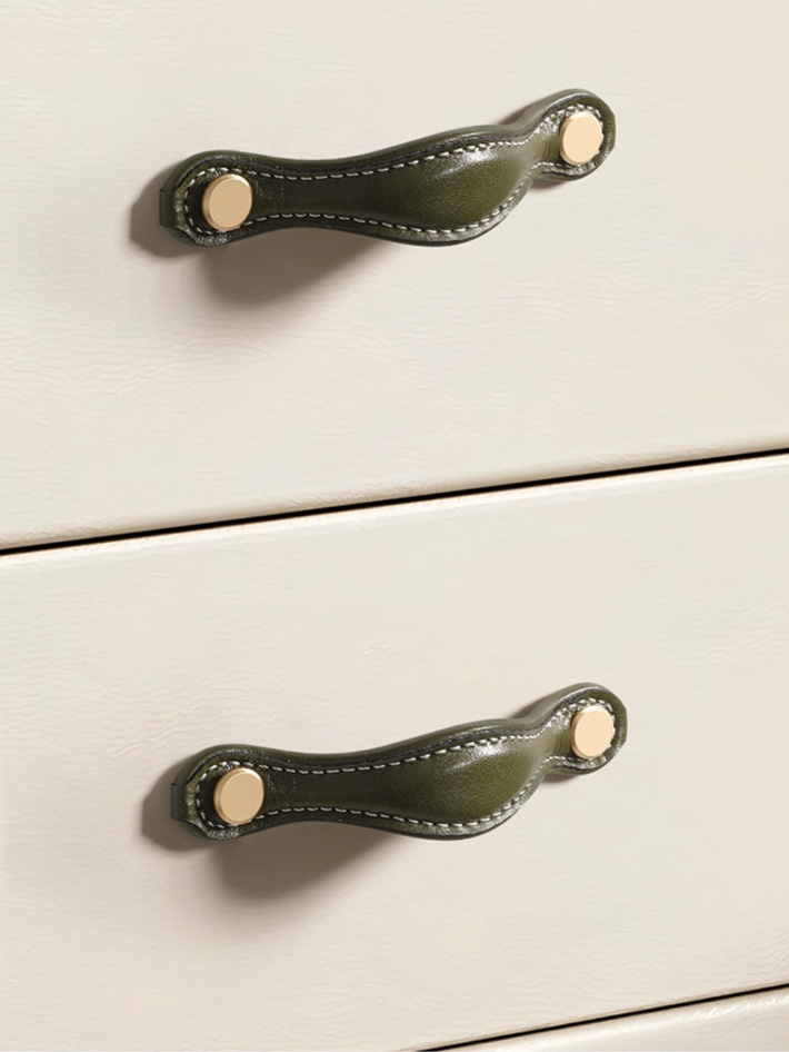 Dark olive green leather-wrapped drawer pulls, curved handles with gold accents, on light beige cabinets.
