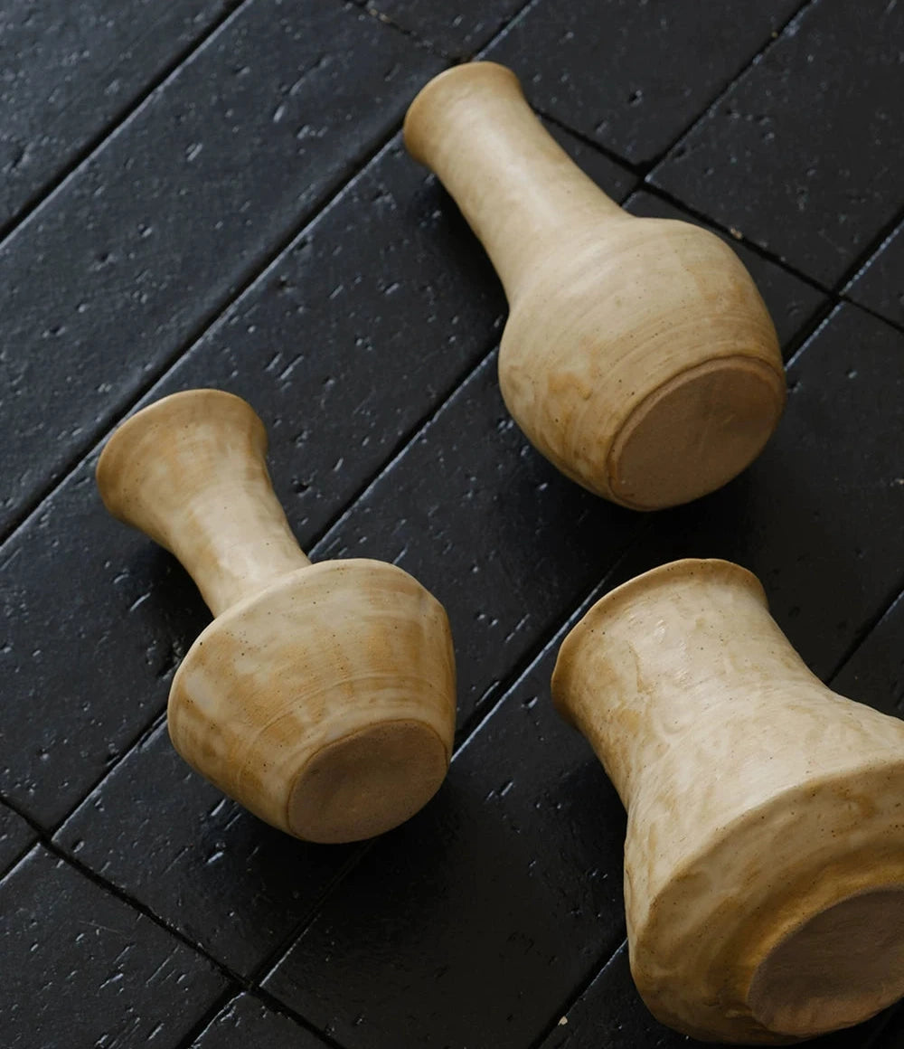 A small, hand-thrown ceramic vase with a creamy white curd glaze and a textured finish.