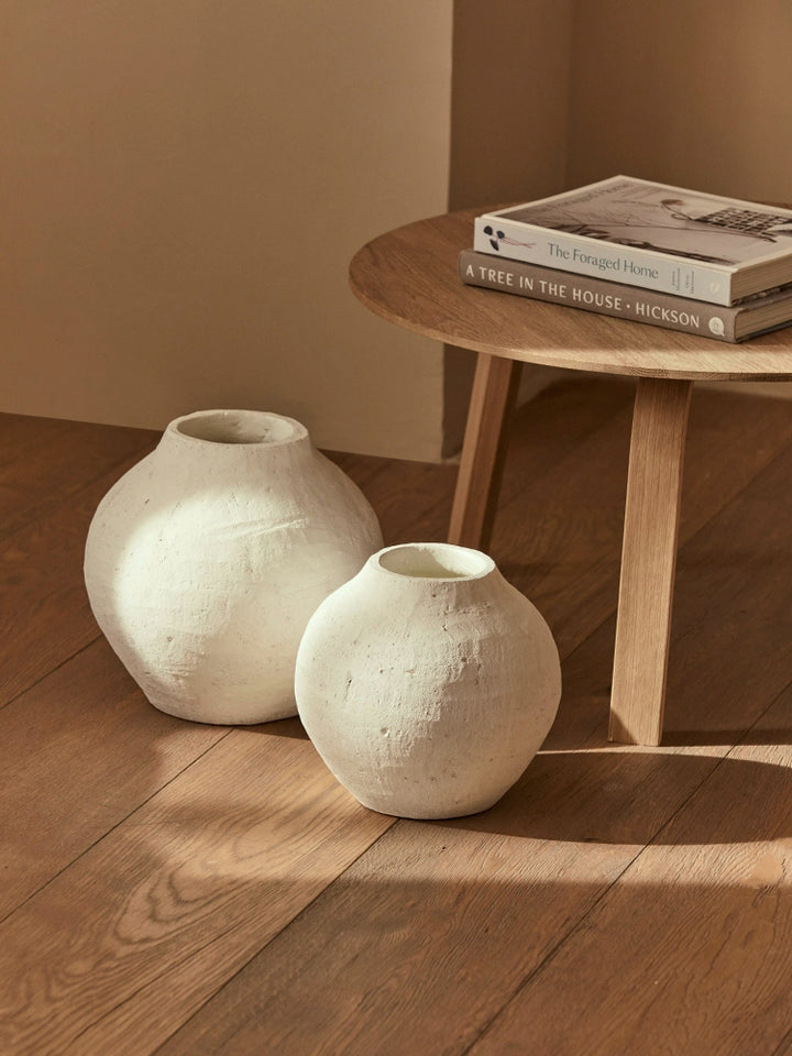 Two white terracotta-style vases on light brown wooden floor.  Decorative, handmade look.