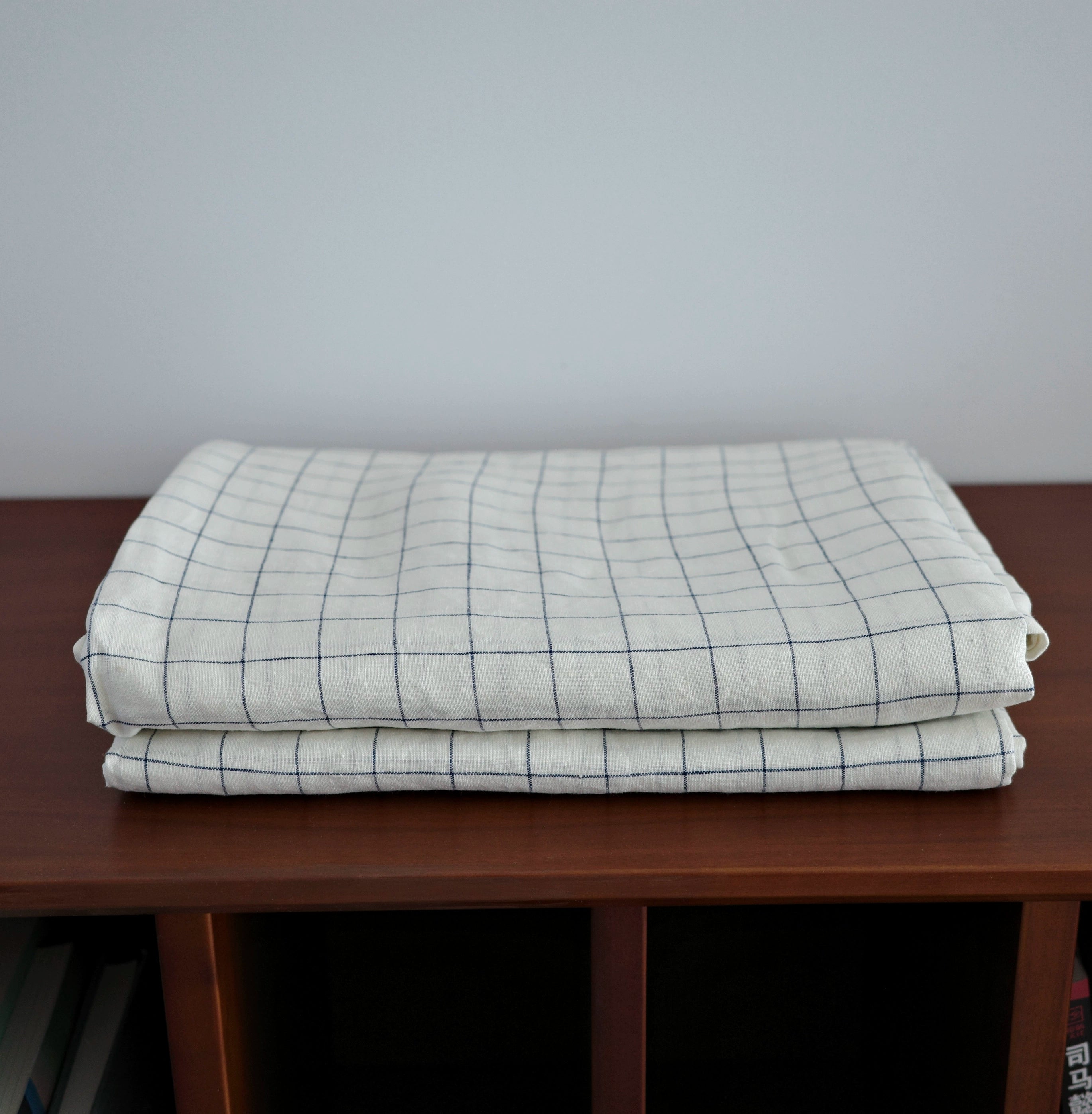 French Linen Striped Bedding Set - Folded white linen with navy stripes on a wooden surface