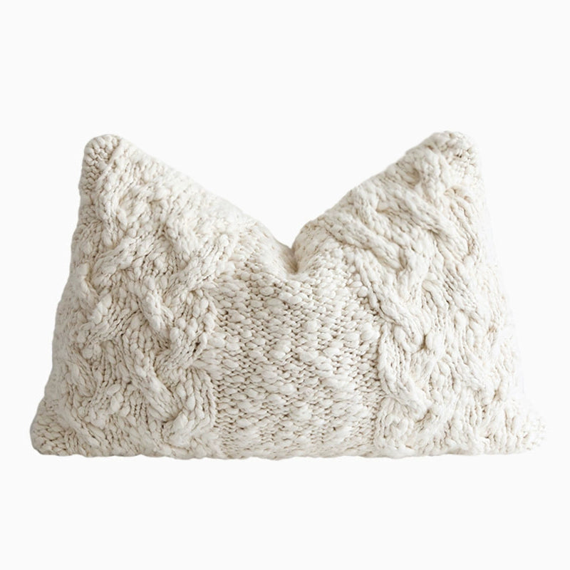 Off-white cable knit throw pillow with textured detail. Cozy knitted decorative pillow.