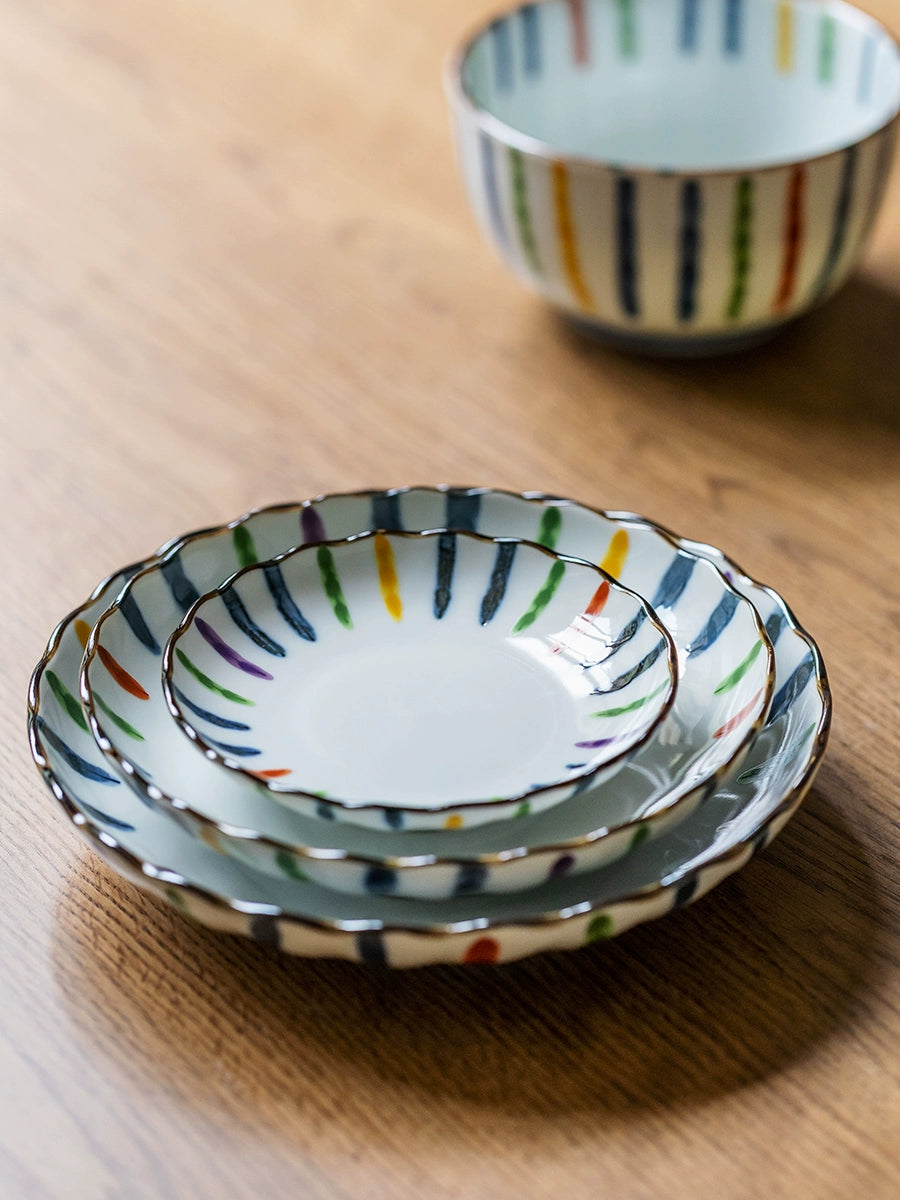 Colorful Striped Japanese Dinnerware Set: ceramic bowls & plates with vibrant vertical stripes on wood.