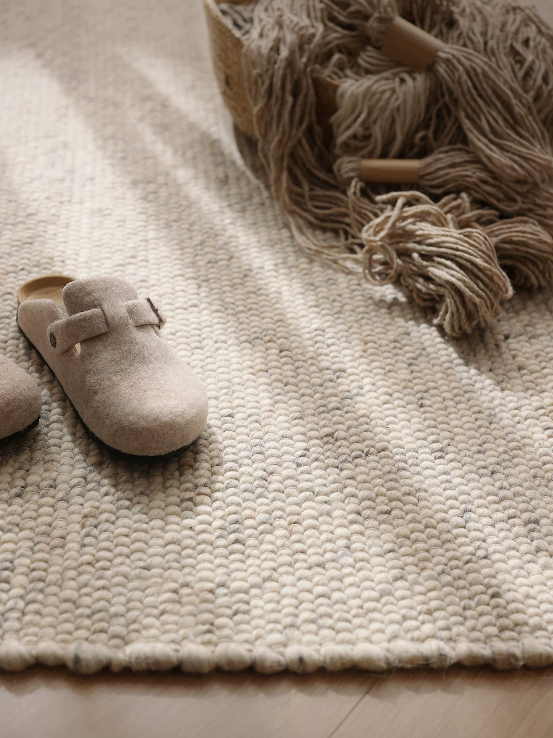 Textured wool rug in neutral living room setting with slippers