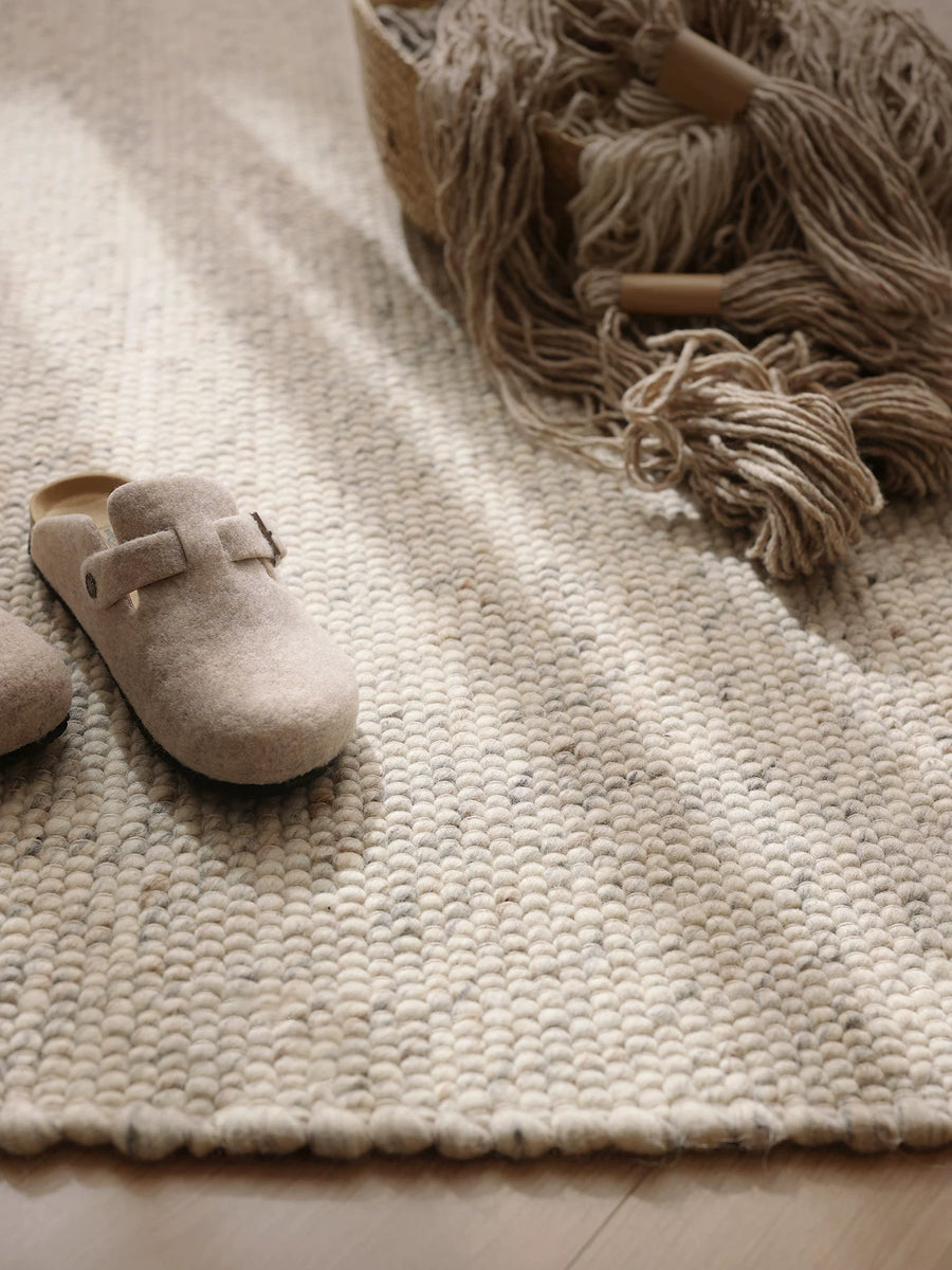 Textured wool rug in neutral living room setting with slippers