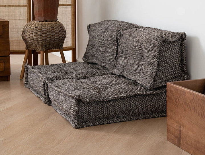 Beige modular sofa, two-seater, with textured fabric, placed on light-colored wooden floor, in a modern living room.