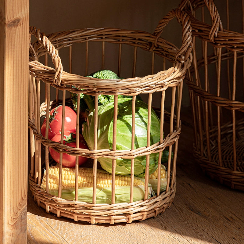 Round woven wicker basket with handles, filled with fresh vegetables like cabbage, tomatoes, corn, and broccoli.