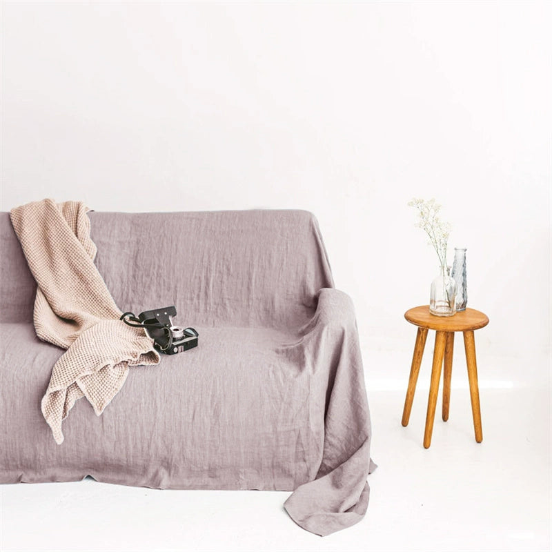 Mustard yellow linen sofa throw blanket draped over a sofa with a beige throw and camera.