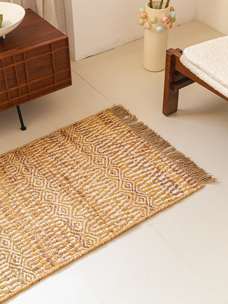 Beige and gold patterned rug with fringe.