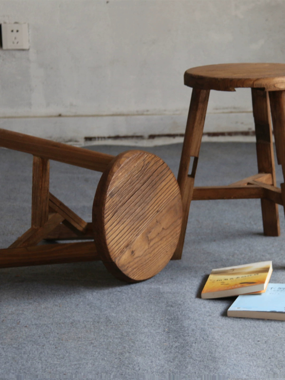 Antique wooden stool, rustic round footstool, Chinese style furniture on grey carpet.