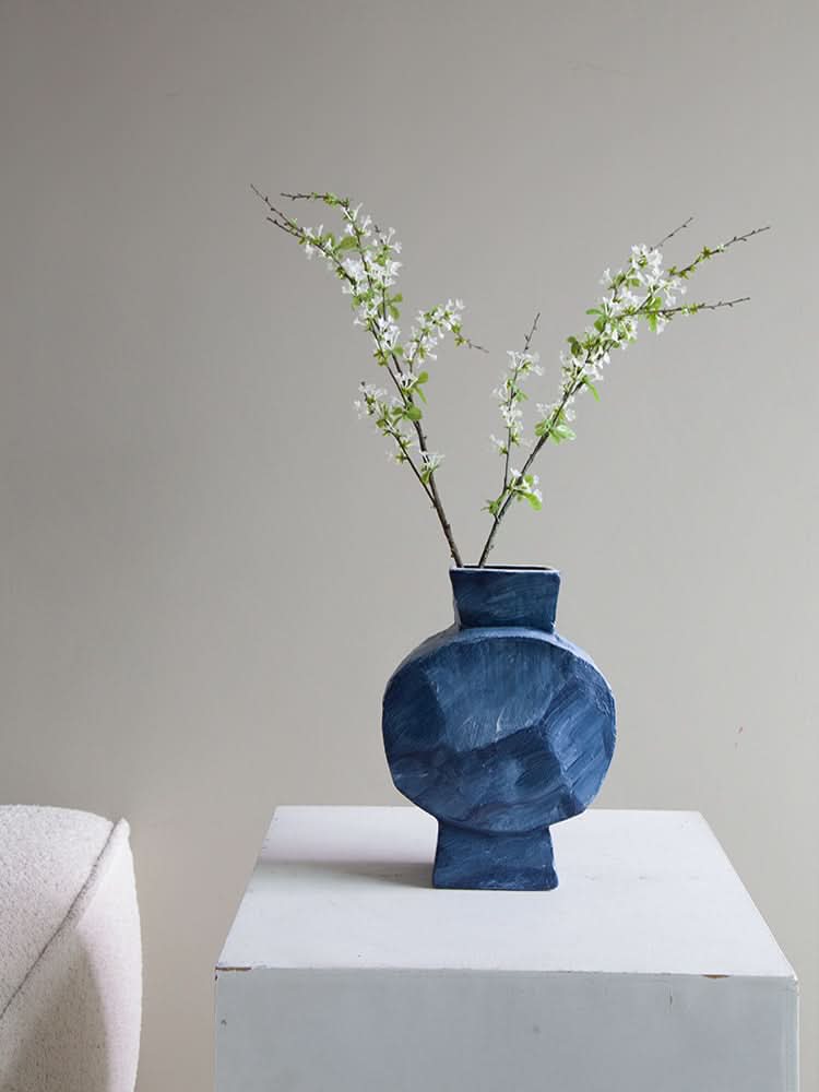 Dreamy Abstract Vase in deep blue textured ceramic with white floral branches on a white pedestal.