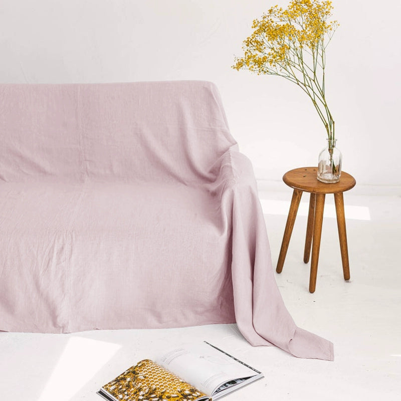 Lavender linen sofa throw blanket on a white couch, with yellow flowers and an open book.