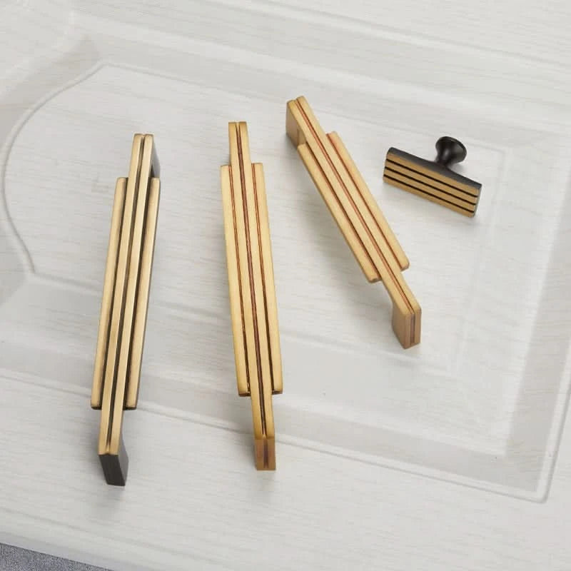 Modern Geometric Cabinet Handles: Gold & black copper design on white drawer.