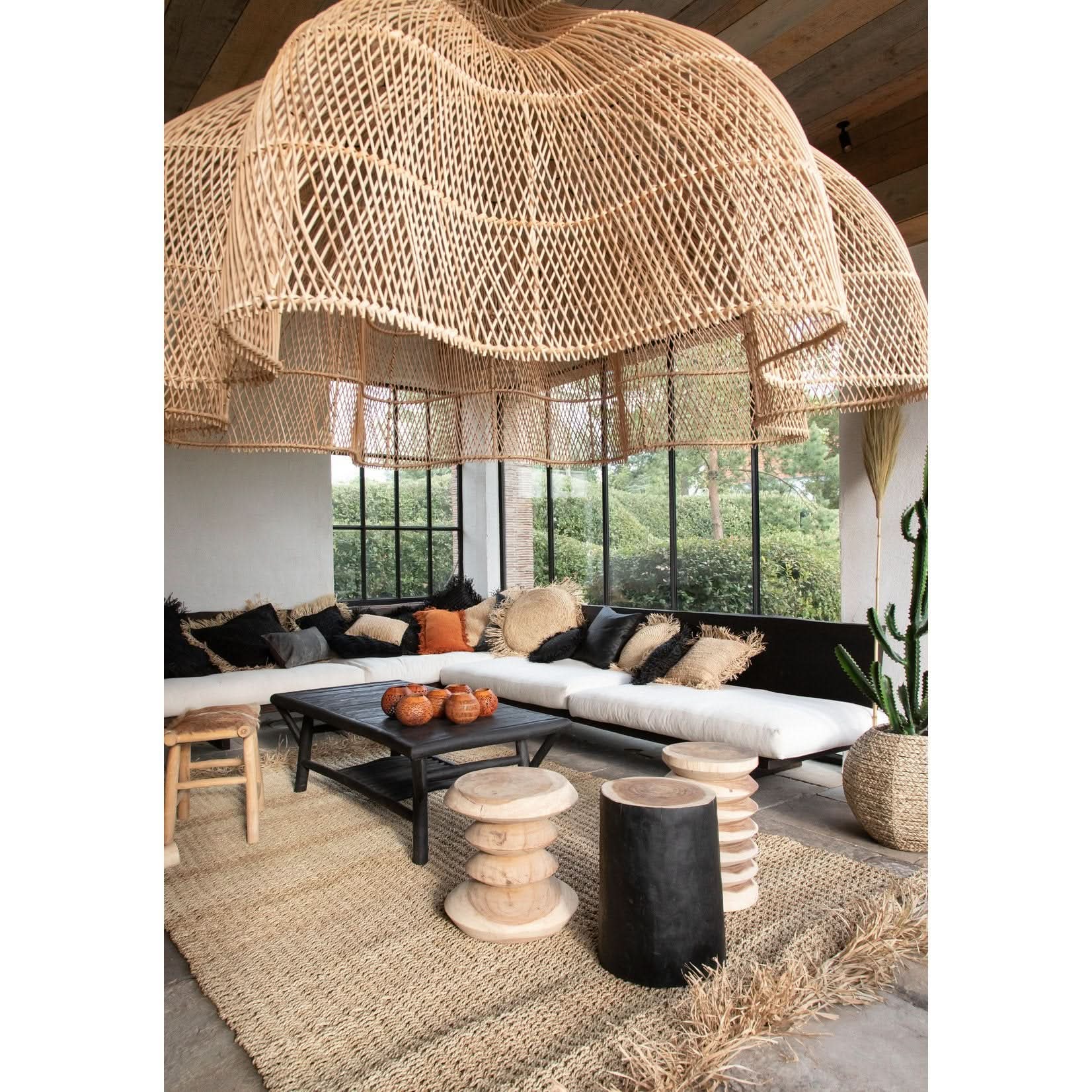 Large, teardrop-shaped rattan pendant light hangs in a sunroom over white sectional sofa.