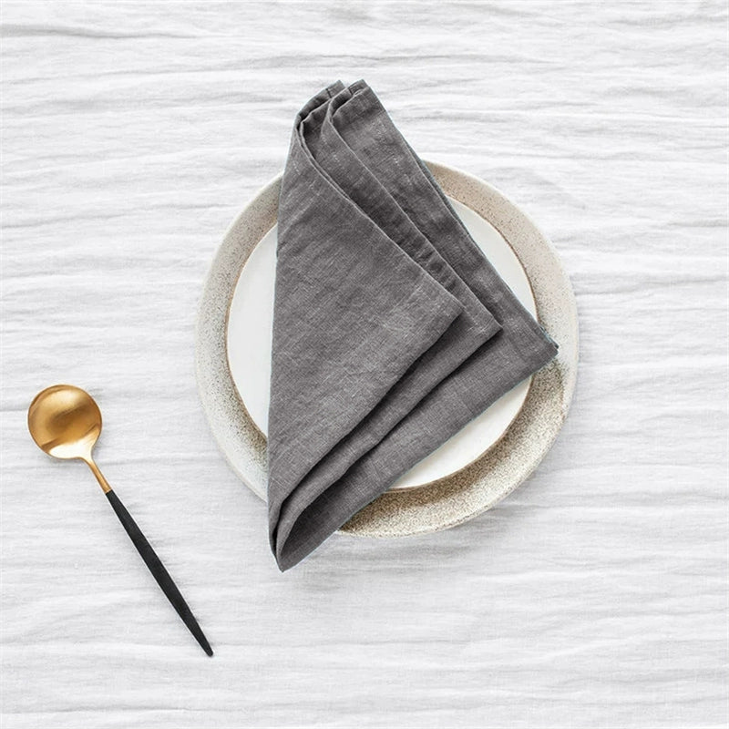 Gray linen table napkins set of 4 on a plate with a gold spoon.