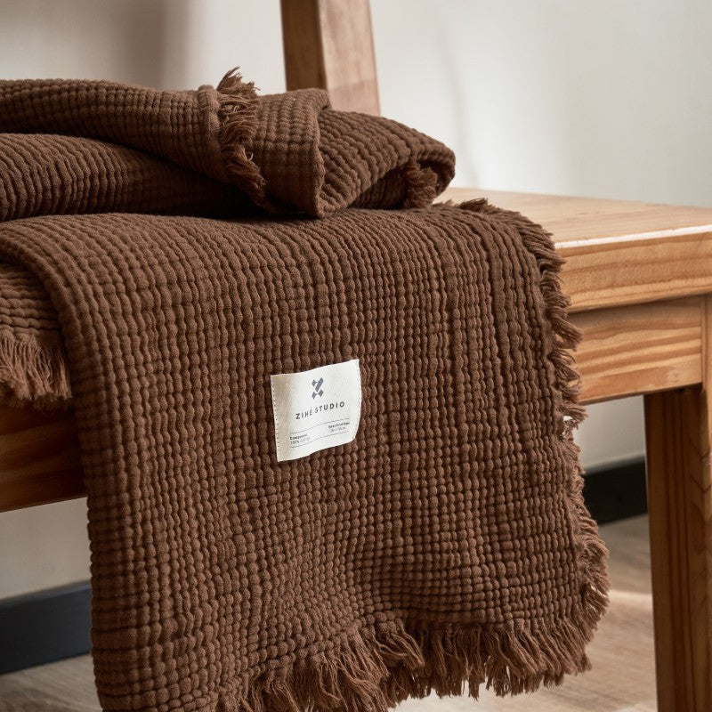 Brown textured throw blanket with fringe.