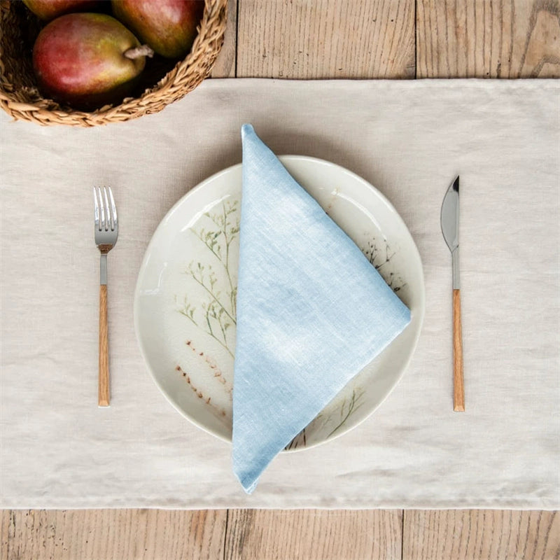 Elegant Linen Table Napkins - Set of 4 in sky blue, on a decorative plate with cutlery.