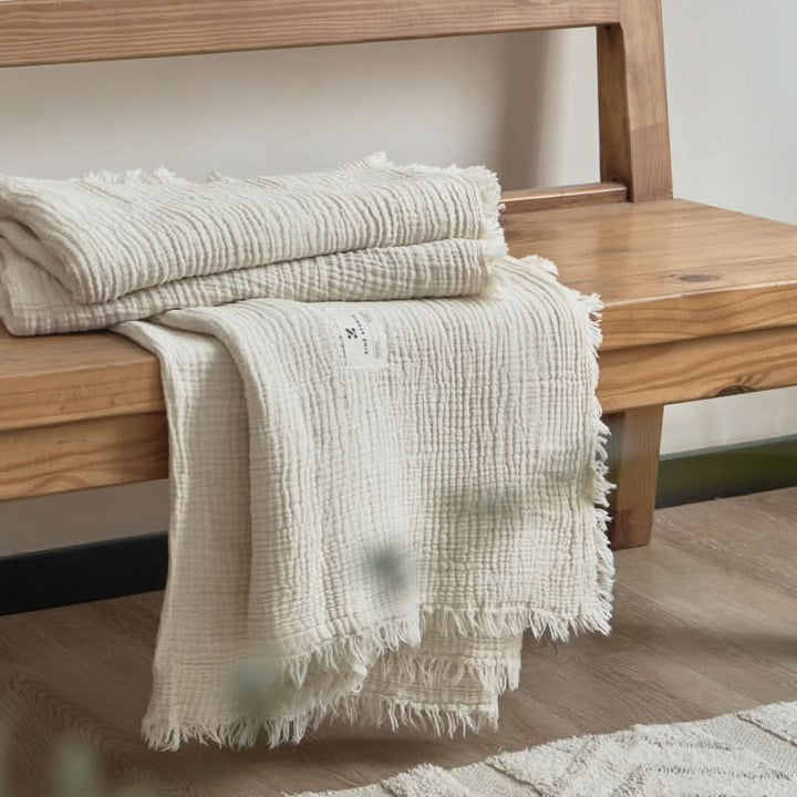 Gray textured throw blanket on wooden bench.