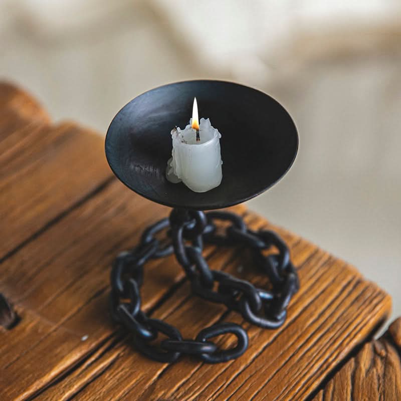 Black Chain Candle Holder with burning white candle on rustic wood surface.