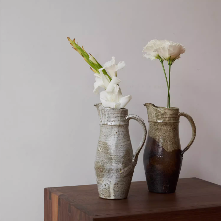 Ceramic Jug Rough Pottery Glaze with white flowers on a wooden surface.
